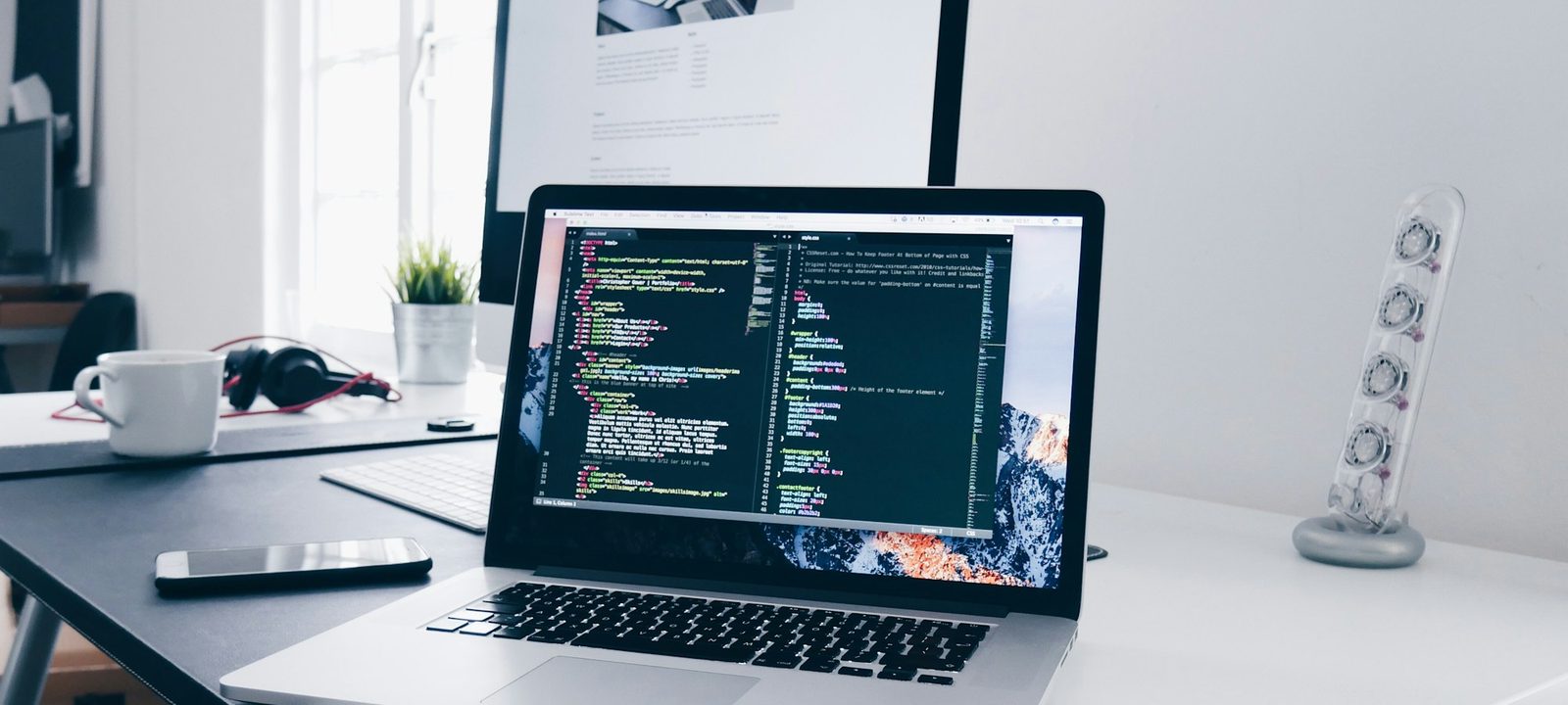 Ordinateur portable affichant du code sur un bureau blanc